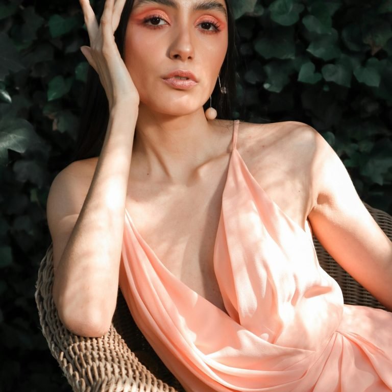 Woman Model in pink dress posing with leaves behind her